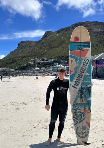Stéphane with a surfboard on a beach in Cape Town